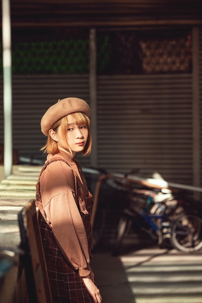 女人在棕色的皮夹克和棕色fedora帽子站在黑色摩托车白天
